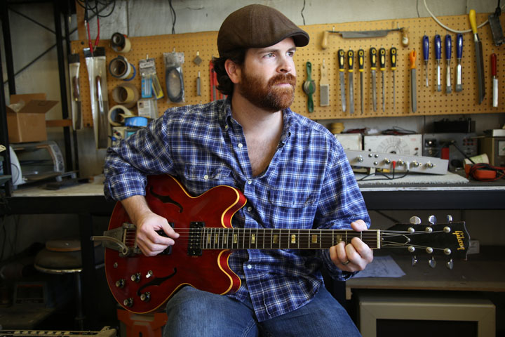 Jer Lile plays a guitar at his shop. The Zionsville guitarist recently completed a documentary that answers several questions about his late uncle, who was also a musician. (Photo by Feel Good Now)