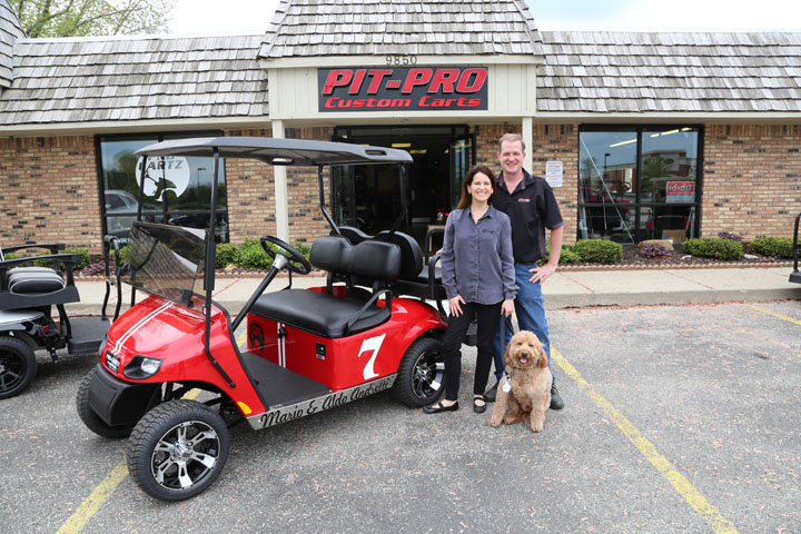 Pau and Mike Nelson and their dog, Oliver, outside of ProCartz. The Carmel company designed a custom golf cart for former racecar drivers and twins Mario and Aldo Andretti. (Photo by Ann Marie Shambaugh)