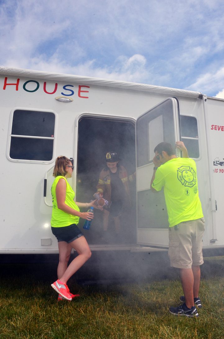 A trailer is set up to mimic a burning house. Zahar Rush exists the house, helped by firefighter Grant Russel and his wife, Lauren Russel, both volunteers. (Photo by Sara Baldwin)